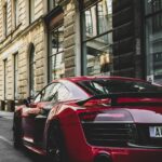 pexels-photo-1545743-1545743 Sleek red sports car parked on a charming historic street in Prague, highlighting urban elegance and powerful design.