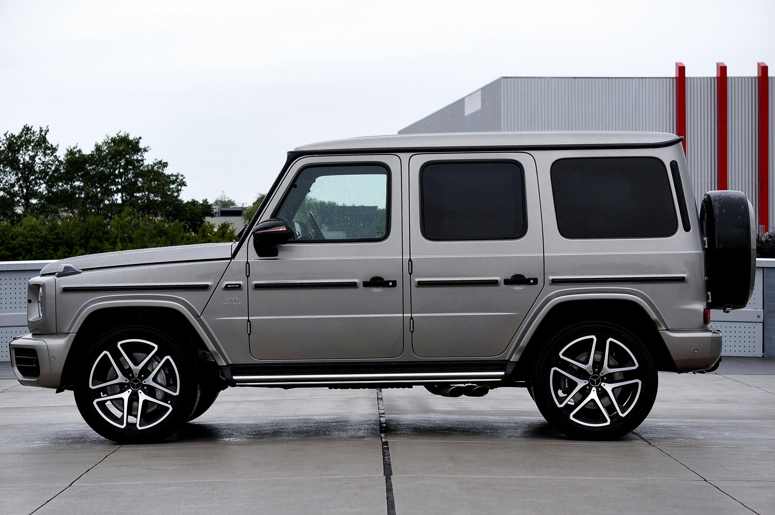 Side view of a silver luxury SUV parked on an urban rooftop with a modern backdrop.
